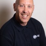 Headshot of Myles Emmett wearing a black shirt with a Giromax logo