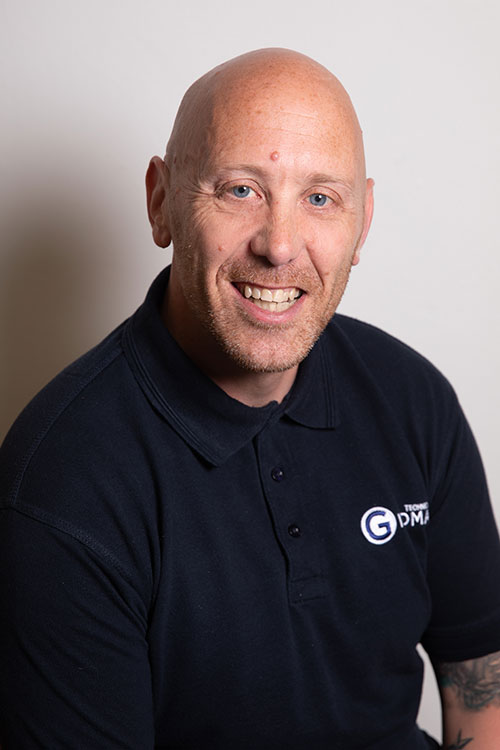 Headshot of Myles Emmett wearing a black shirt with a Giromax logo